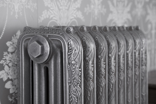 Close-up of a ribbon cast iron radiator showing the bleed valve